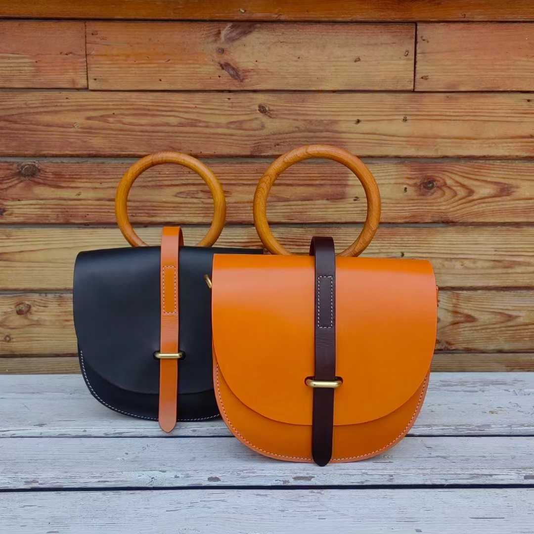 Two leather bags in orange and black with wooden ring handles
