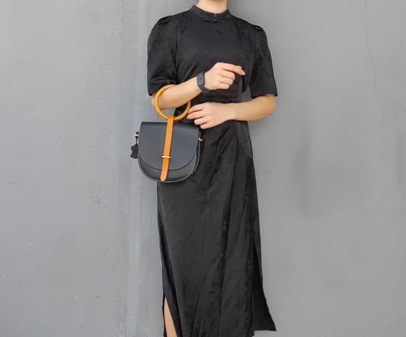 Model carrying black leather bag as handbag